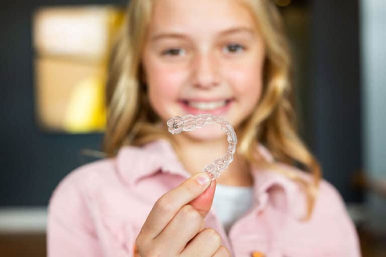 beautiful girl holding clear aligners in her hand and smile.