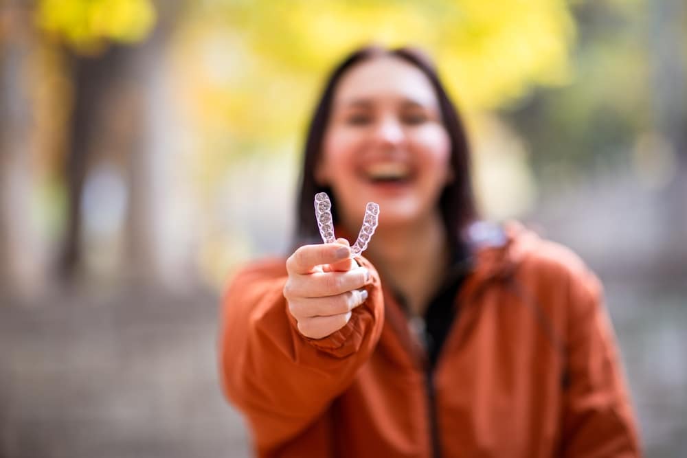 woman holding Invisalign® Johns Creek