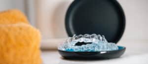 A pair of clear dental aligners resting inside an open black carrying case, ready for travel or use