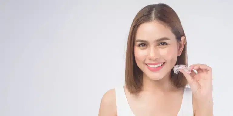 Adult woman holding clear aligner tray for discreet teeth straightening treatment