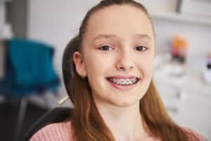 Teen patient with braces smiling during orthodontic visit at dental clinic