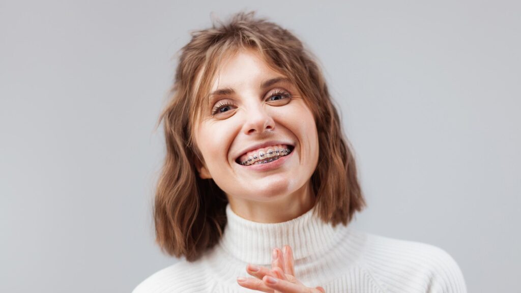 Smiling adult wearing metal braces, showing increased confidence during orthodontic treatment in social and professional settings.